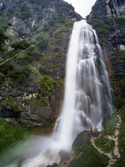Huge waterfall and woman with yellow backpack.