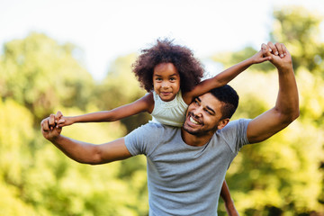 Portrait of young father carrying his daughter on his back