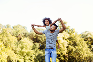 Portrait of young father carrying his daughter on his back