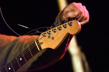 musician's hand is tuning an electric guitar on the stage
