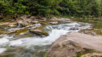 Fototapeta premium Clear water of a mountain river passes through a cascade of boulders. Carpathian mountains, Ukraine. 