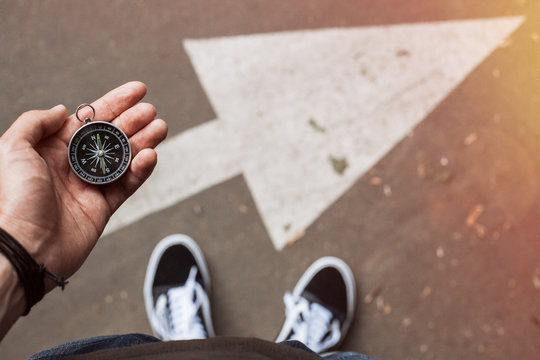 Hipster traveler holding compass in the hand making choice in what direction to go