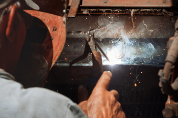 Welder,  erecting technical steel. Industrial steel welder. Craftsman in factory. The welder is engaged in repair of equipment in an industrial plant. Sparks of welding.