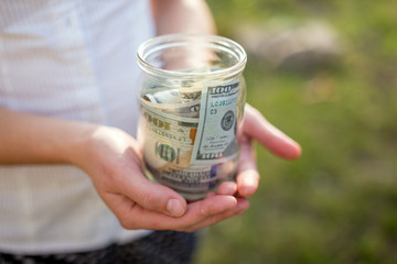 woman hands holding glass jar with coins