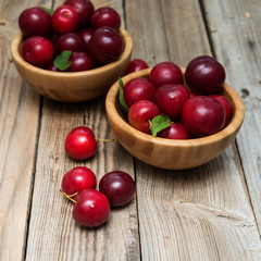 fresh plums in bowls  on wooden background