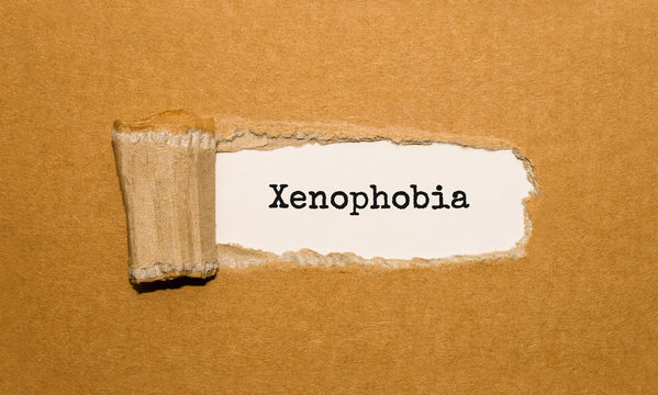 The text Xenophobia appearing behind torn brown paper