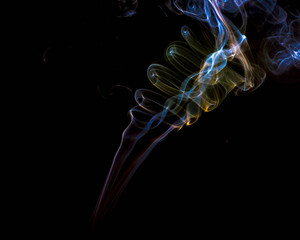 multicolored smoke dissipates in the air on an isolated black background