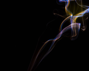 multicolored smoke dissipates in the air on an isolated black background