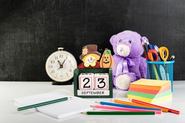 National Hunting and Fishing Day, traditional American holiday. Cube shape calendar for September 23, open notebook, stickers, pencils, table clock and teddy bear on light table