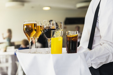Close up of waiter holding a tray with any drinks.