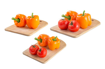 Orange pepper and tomatoes on a cutting board on isolated background