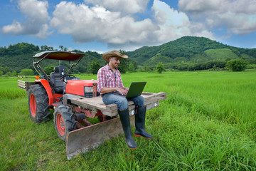 Portrait of a farmer sitting on a tractor smiling © sirisakboakaew