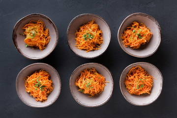 Set of plates with russian korean salad on black background