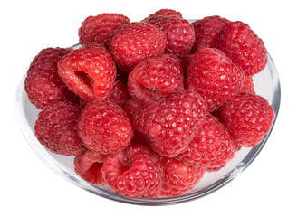 Ripe red raspberries in a glass bowl. Pile of juicy sweet fruits isolated on white background.