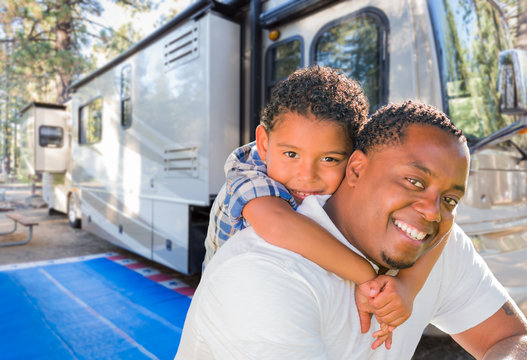 African American Father With Mixed Race Son In Front of Their Beautiful RV At The Campground.