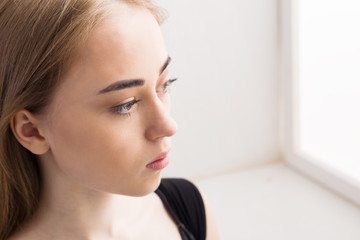 Fototapeta premium Portrait of a sad young girl on white background