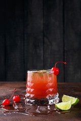 Red cocktail with lime on brown table background