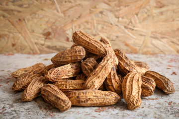 Pile raw peanuts in shell on wooden background