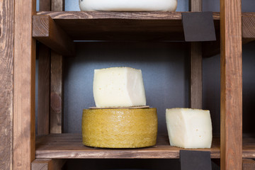 Hard cheese in wheel and piece on grocery shop shelf