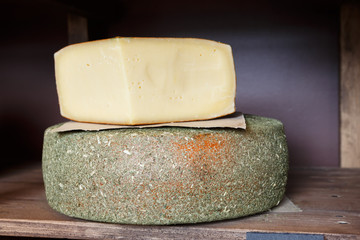 Hard cheese as wheel and piece on grocery shop shelf closeup