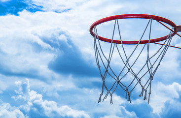 red basketball basket, ring, against a beautiful sky with snow-white clouds, symbolizes devotion to the sport