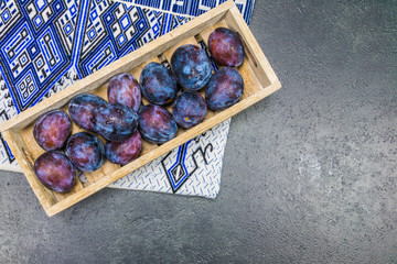 fresh plums with waterdrops on it in a wooden box