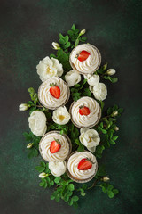 Fototapeta na wymiar vanilla cupcakes with fresh strawberry and white roses flowers on dark green background