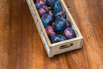 fresh plums with waterdrops on it in a wooden box