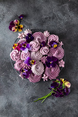 composition of various blueberry meringues and pansies flowers on dark grey  background