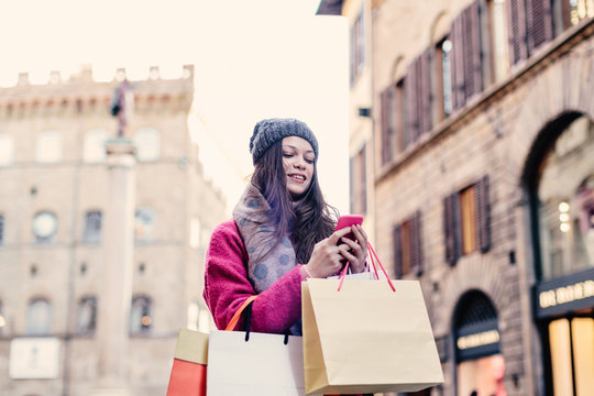 Young woman shopping in the streets of Florence looking at phone