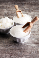 Bowl with white sand and lump sugar on grey background