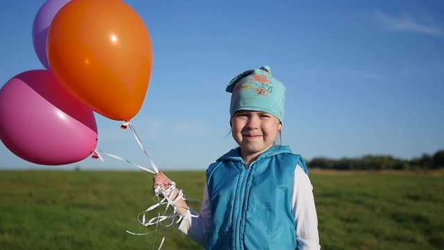 Cute Girl standing with balloons in field