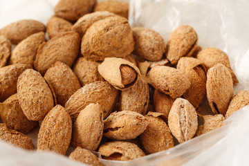 Pile of almond in shell in plastic bag, selective focus