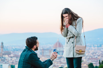 Young man proposing to his girlfriend against view of Florence from above