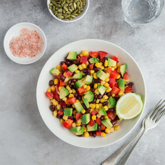 Avocado, black  bean, corn and bell pepper salad in white bowl