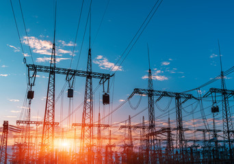 distribution electric substation with power lines and transformers, at sunset.