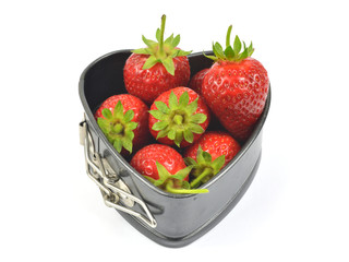 Fresh strawberries in a backing heart shaped souffle pan on white background