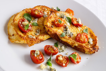 french toasts with roasted tomatoes, gorgonzola, and parmesan decorated with basil leafs