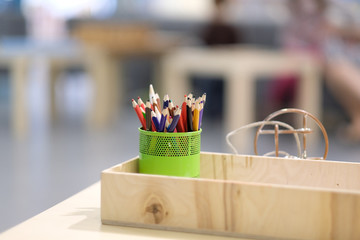 Color pencils in a glass and a wooden box for accessories in the children's development center