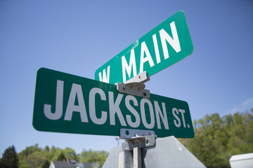 A street sign against a blue afternoon sky with trees in the background