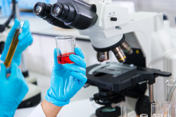 Close up sample test chemical on hand scientist with microscope