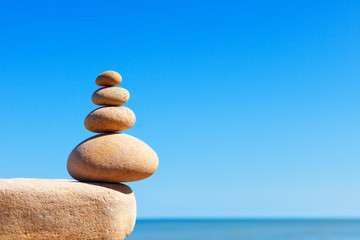 Rock zen pyramid of white stones on a background of blue sky and sea.