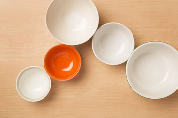 Five empty bowls on light wood background, Flat top view