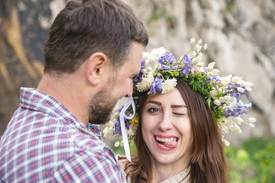 Portrait of a foolish girl in a wreath of flowers next to her future husband