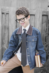 Young preteen boy smiling, holding books, pencils and leather bag outdoors, ready for school