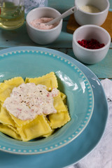 Ravioli with mushrooms and with bacon and sour cream sauce. Blue wooden table, blue plates.