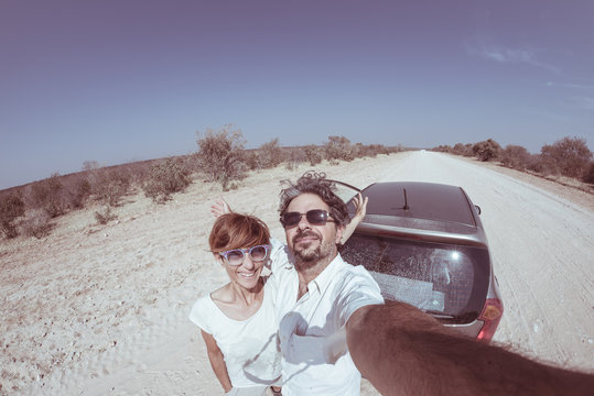 Adult couple selfie on road trip in the desert, Namib Naukluft National Park, travel destination in Namibia, Africa. Fisheye, people traveling and adventure, toned desaturated image.