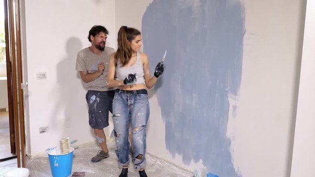 Happy cute couple painting new home dancing pop music dolly shot