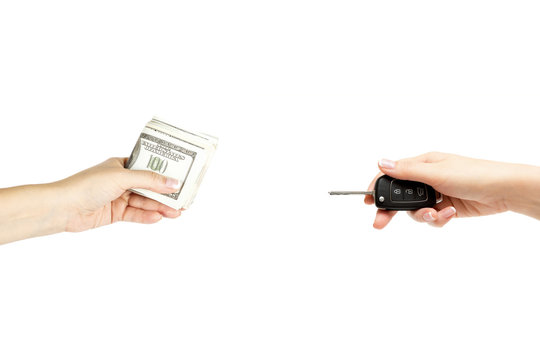 Holding female hands with keys of car and stack of dollars on white background.