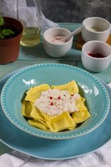 Ravioli with mushrooms and with bacon and sour cream sauce. Blue wooden table, blue plates.